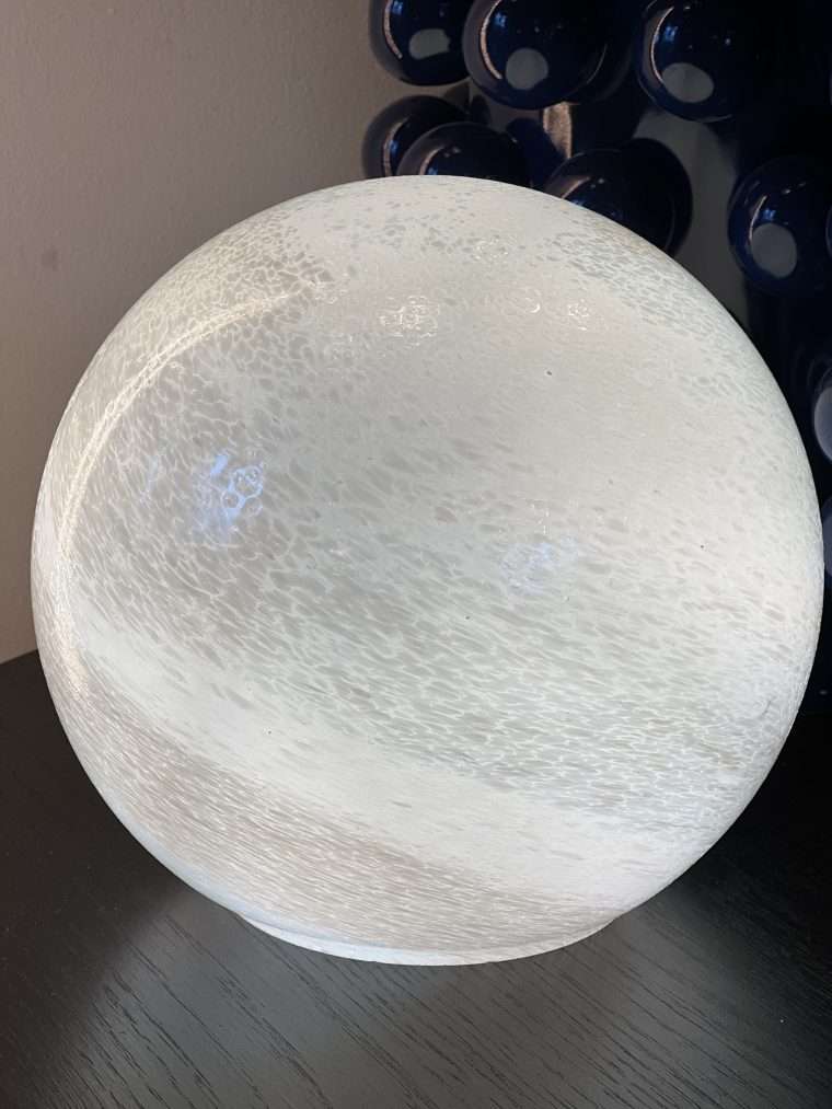 Lampe boule effet nacre 20 cm Vous serez séduit par le soin apporté aux détails de ce luminaire qui semble tout droit venu du ciel ! Sa forme ronde et sa matière nacrée en font une véritable lune miniature. Dimensions : 20 cm
